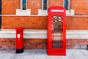 Red telephone and post box in street with historical architecture in England