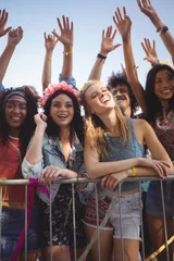 Rolgordijnen Happy female friends standing by railing at music festival © WavebreakMediaMicro