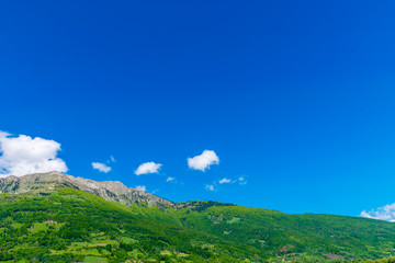A picturesque mountain peak against a blue sky with white clouds.