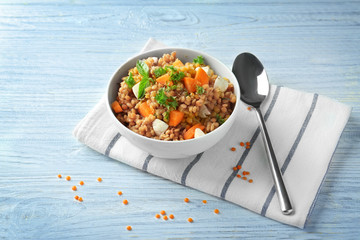 Bowl of lentil salad with vegetables on table