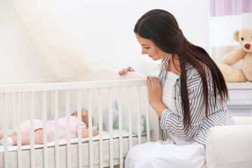 Mother lulling baby in crib at home