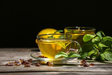 Cup of mint tea on table against black background