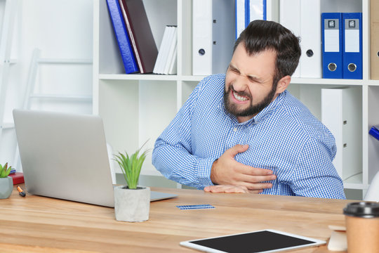 Young man suffering from chest pain in office