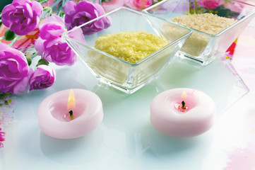 Fototapeta na wymiar Wellness concept with candles, pink flower, bowls with bath salt in pastel coloring 