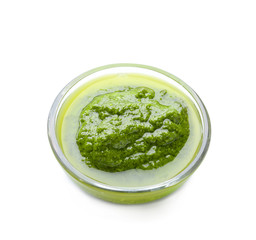 Bowl with delicious basil pesto sauce on white background