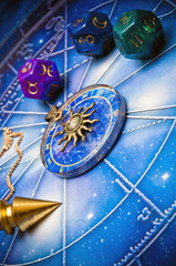 zodiac ring, pendulum, dice with astrology symbols lying on horoscope
