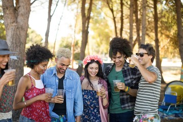 Happy friends holding beer glasses at campsite