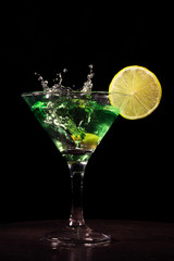 Green cocktail with splash on black background