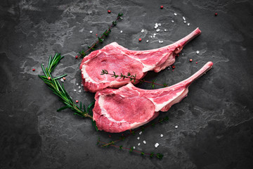 raw veal steak on the bone on the dark stone - obrazy, fototapety, plakaty