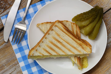 Crunchy toast with cheese and pickled cucumber on the side
