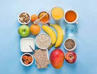 Healthy Food Fiber Source Breakfast Oatmeal Honey Fruits Apples Banana Mango Orange Juice Water Green Tea Nuts. Light Blue Tabletop. Modern Funky Square Flat Lay Top View.