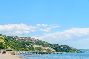 ALBENA, BULGARIA - JUNE 16, 2017: The Black Sea shore, green hills with houses, blue clouds sky. City Balchik coast