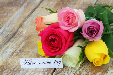 Have a nice day card with colorful rose bouquet on rustic wooden surface
