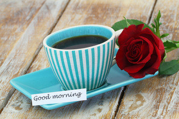 Good morning card with cup of coffee and red rose on rustic wooden surface
