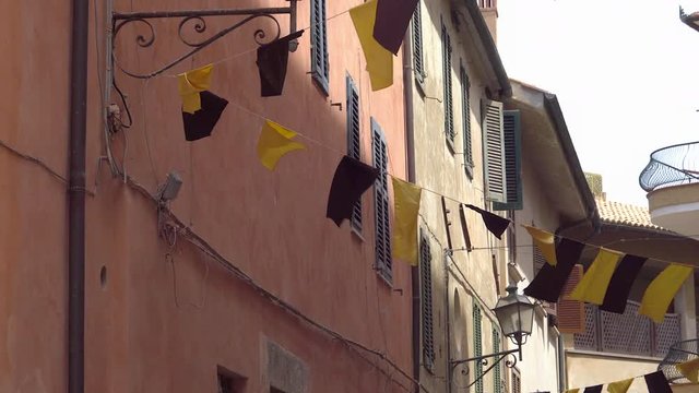 The hanging flaglets on the narrow street of Monte Argentario with the houses and aparments on the side of the street