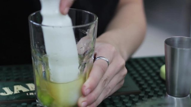 A female bartender muddles a cocktail glass 