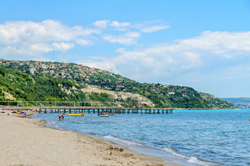 ALBENA, BULGARIA - JUNE 16, 2017: The Black Sea shore, green hills with houses, blue clouds sky. City Balchik coast
