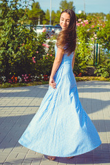 Fototapeta premium Beautiful young skinny girl walks around the city in a long dress in a cage and enjoys the day