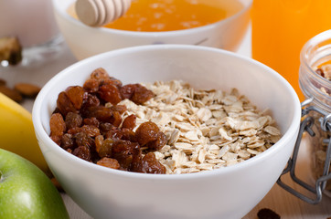 Bowl of oatmeal and raisins. Honey, bananas, green apples, nuts
