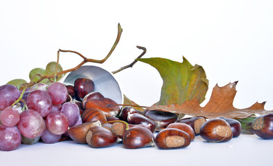 frutta autunnale, castagne e uva  composizione con castagne ed uva, foglie appassite, sfondo bianco