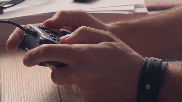 Man playing video game. Close up of adult caucasian male hands using joypad controller for entertainment and fun, enjoying leisure time for work break in office.