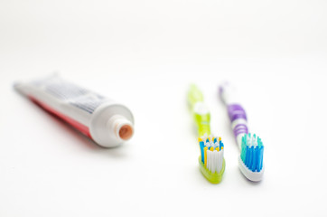 On a white background lies toothpaste and two brushes