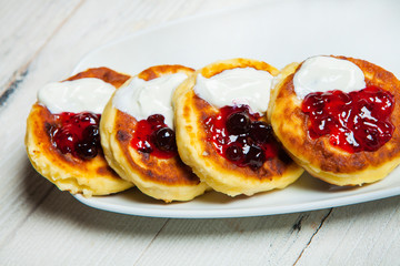 Russian traditional syrniki cottage cheese pancakes breakfast on the plate. Russian cheesecakes with raisins on a white plate. Cheese fritters.
