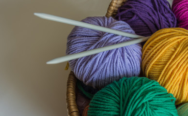 Nahaufnahme von Wolle in einem Korb mit Stricknadeln