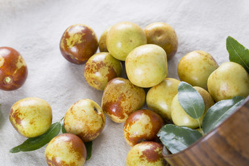 Closeup of fresh jujube fruit in a wooden bowl.