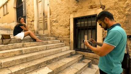 Young couple making photos on narrow Mediterranean street on vacation