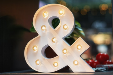 A huge illuminated ampersand on the table - 175737501