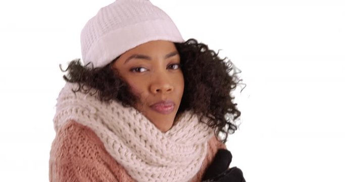Close up of pretty black female in winter clothes shivering on white background