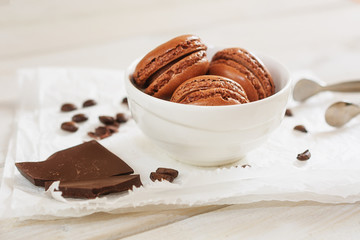 Pieces of chocolate with loose coffee beans and coffee flavored macarons presented on a white napkin