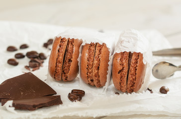 Pieces of chocolate with loose coffee beans and coffee flavored macarons presented on a white napkin