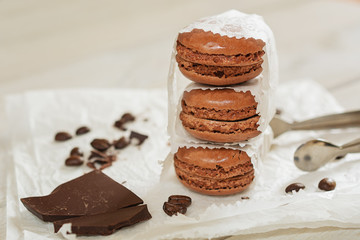 Pieces of chocolate with loose coffee beans and coffee flavored macarons presented on a white napkin