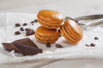 Pieces of chocolate with loose coffee beans and coffee flavored macarons presented on a white napkin