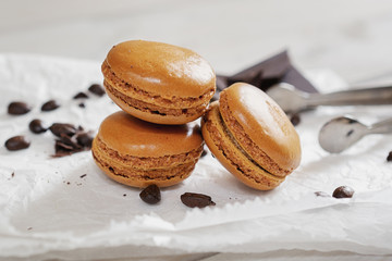Pieces of chocolate with loose coffee beans and coffee flavored macarons presented on a white napkin