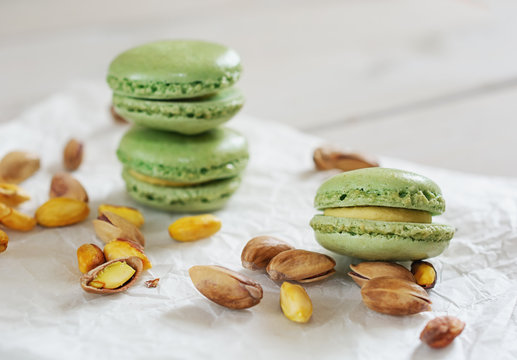 Peeled and unpeeled pistachio nuts  and pistachio flavored macarons presented on a white napkin presented