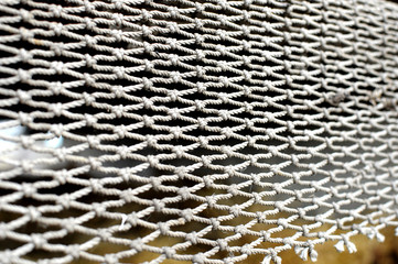 Rope mesh on the blurry background of stack of hay. Texture backdrop.
