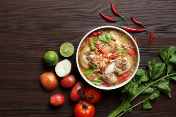 Oxtail soup in white bowl and vegetables for ingredient soup on wooden table.Selective focus and space for texts.