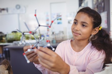 Elementary student examining molecule model - Powered by Adobe