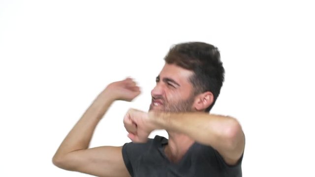 slow motion ecstatic smiling guy in grey t-shirt dancing wildly full of energy making uncontrolled movements expressing total happiness over white background. Concept of emotions