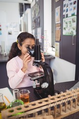 Elementary student looking through microscope at laboratory