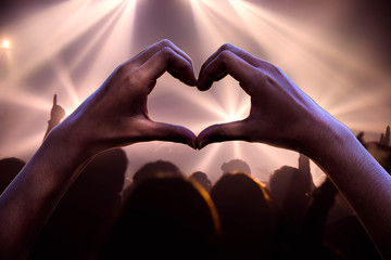 people show hand shape heart at rock concert.