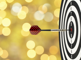 close up dart arrow hitting on target center on bullseye in dartboard with blurred golden bokeh...