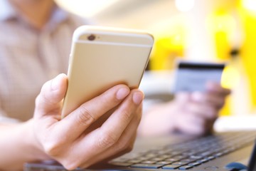 business man hands holding credit card and using phone and computer laptop. Online shopping purchase Sell or Payment.