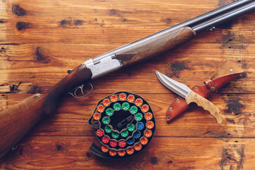 Jacht uitrusting. Shotgun, jachtpatronen en jachtmes op houten tafel.