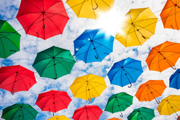 Many colorful umbrellas hanging in the sky