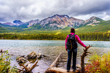 Woman hiker at the edge of Pyramid Lake, near the town of Jasper in Jasper National Park in the Canadian Rockies. Pyramid Mountain in the background