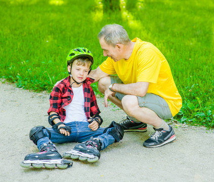 Father talk with son who has fallen at skating on the roller skates